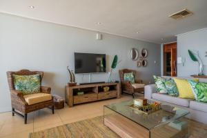 ウムドロティにあるLuxury Beachfront Apartment - 30 Degrees Umdlotiのソファと椅子とテレビのあるリビングルーム