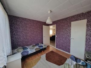 1 dormitorio con paredes moradas, cama y espejo en Villa Anna en Rauma