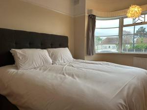 a bedroom with a large white bed with a window at 4 bed family home + Garden Twickenham. in Twickenham