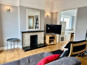 ein Wohnzimmer mit einem Kamin und einem TV in der Unterkunft 4 bed family home + Garden Twickenham. in Twickenham