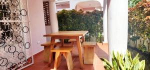 une table en bois et des bancs dans une pièce ornée de plantes dans l'établissement Alojamiento Fred Bayahibe, à Bayahibe