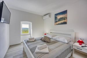a white bedroom with a large bed and a television at Ferienlandhaus Zvanya in Kozljak +32 photos