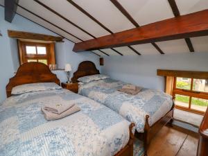 Gallivantin Cottage في ليبرن: سريرين في غرفة نوم مع نافذتين