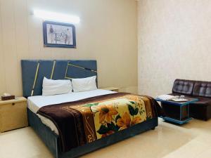 um quarto com uma cama com um cobertor e uma cadeira em Hotel Royal Fort em Lahore