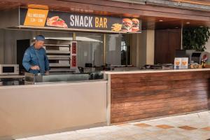 a man standing behind the counter of a sushi restaurant at ALEGRIA Florida Park in Santa Susanna
