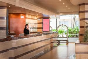 a woman talking on a cell phone in a lobby at ALEGRIA Florida Park in Santa Susanna