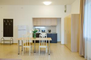 
a kitchen with a table, chairs and a refrigerator at ApartHotel Imeretinsky - Parkovy Kvartal in Adler
