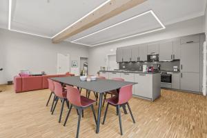 巴斯查哈吉的住宿－Lénger Schoul，厨房以及带黑色桌子和粉红色椅子的用餐室。