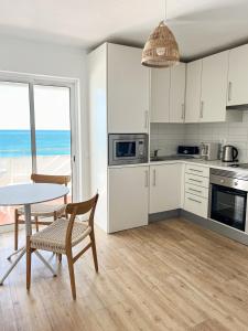 a kitchen with white cabinets and a table and a table and chairs at Apartamentos Rossio Mar in Albufeira