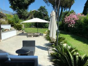 une terrasse avec un parasol blanc, une table et des chaises dans l'établissement Villa degli Azzurri, à Rome