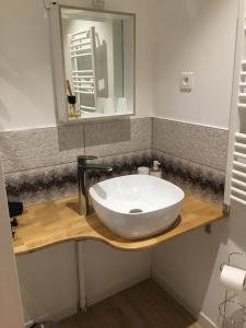 a bathroom with a white sink on a wooden counter at Aux Lacs et Cascades in Songeson