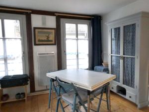 - une salle à manger avec une table et deux fenêtres dans l'établissement L'avocette élégante, à Saint-Valery-sur-Somme