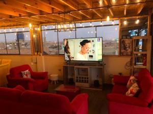 sala de estar con 2 sillas rojas y TV de pantalla plana en The Big blue house en Chimbote