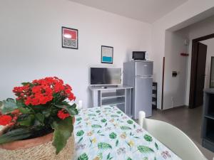 una habitación con una mesa con un jarrón de flores rojas en Villaggio Camping Lungomare, en Cropani