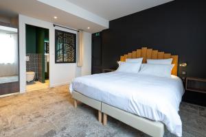 - une chambre avec un grand lit blanc et une tête de lit en bois dans l'établissement Hôtel Les Pins, à Saint-Trojan-les-Bains