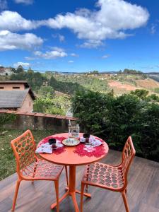 a table and chairs on a wooden deck with a view at Vila husky pousada in Campos do Jordão
