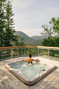 una mujer en un jacuzzi en una cubierta en Auberge de Montagne des Chic-Chocs Mountain Lodge - Sepaq en Sainte-Anne-des-Monts