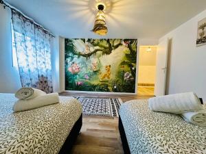 een slaapkamer met 2 bedden en een schilderij aan de muur bij Maison Le M - Disneyland JO Paris 2024 Parking in Chessy