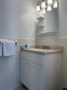 La salle de bains est pourvue d'un lavabo blanc et d'un miroir. dans l'établissement The Even'tide, à Wellfleet