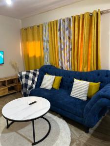 uma sala de estar com um sofá azul e uma mesa branca em Cozy 1br apartment in King’ong’o-Nyeri em Nyeri
