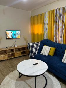 Cozy 1br apartment in King’ong’o-Nyeri في نيري: غرفة معيشة مع أريكة زرقاء وطاولة بيضاء