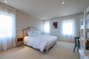 - une chambre avec un lit blanc et 2 fenêtres dans l'établissement Hôtel Les Pins, à Saint-Trojan-les-Bains