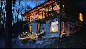 una casa en el bosque por la noche con luces en Nature Eco Suite in Wakefield Quebec, en Wakefield