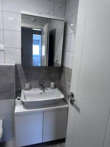 a white bathroom with a sink and a mirror at Apartman Pionirska dolina in Sarajevo