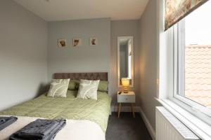 una camera da letto con un letto con un piumone verde e una finestra di Huckleberry House a Lowick