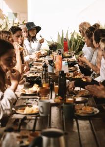 un grupo de personas sentadas en una mesa larga comiendo comida en Mirabilia Luz - Altavista en Luz