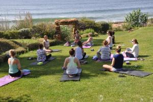 a group of people sitting in the grass in a yoga class at Mirabilia Luz - Altavista in Luz