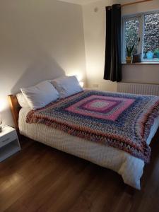 a bedroom with a bed with a colorful blanket on it at Felicity Cottage in Kiltegan