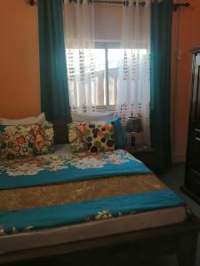 um quarto com uma cama com cortinas azuis e uma janela em Bertoua : Bel appartement en centre-ville em Bertoua