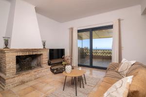 Le Mar Villa في فاسيليكوس: غرفة معيشة مع أريكة ومدفأة