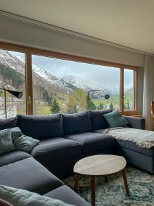a living room with a blue couch and a large window at *TOP* moderne Wohnung im Herzen von Andermatt in Andermatt