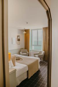 ブリニョガン・プラージュにあるHôtel de la Merのベッド2台と窓が備わるホテルルームです。