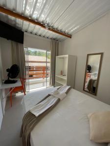 a bedroom with a large white bed and a large window at Pousada Uchimura in Itapecerica da Serra