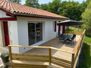 een houten terras met een tafel en een parasol bij Maison calme IHESA in Bidache