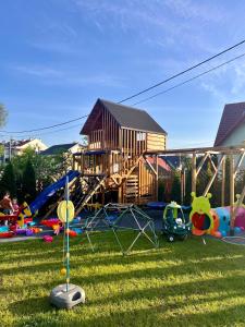 a playground with a house and many toys in the grass at Domki Dobre Kąty Sauna&Balia in Kąty Rybackie