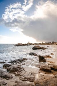 a beach with rocks and the ocean with a lighthouse at Hôtel de la Mer in Brignogan-Plage