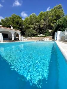 una piscina de agua azul frente a una casa en La Villa del Sol, en Oliva