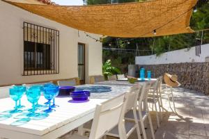 een witte tafel met blauwe glazen en stoelen bij La Villa del Sol in Oliva
