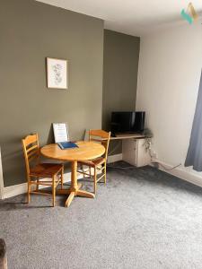 Zimmer mit einem Tisch und Stühlen sowie einem TV in der Unterkunft Milton Road Flat 2 - TSAC in Hartlepool