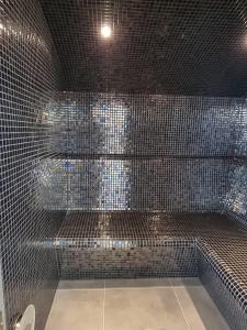 baño de azulejos negros con ducha y aseo en 27 Tower View Pevensey Bay Holiday Park en Pevensey
