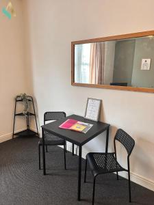 una mesa negra con 2 sillas y un espejo en Milton Road Flat 1 - TSAC, en Hartlepool