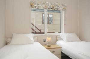 two beds in a room with a window at Lodge 69 at Riviera Bay Coastal Retreat in Brixham +28 photos