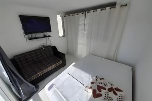 Habitación blanca pequeña con TV y mesa en lindo apartamento no recreio bem pertinho da praia en Río de Janeiro
