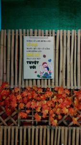 a sign on a wooden fence next to a bunch of leaves at Let's go CAN THO - CAN THO FARMSTAY in Ấp Phú Thạnh (4)
