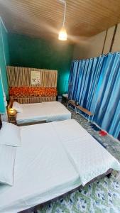 two beds in a bedroom with blue curtains at Let's go CAN THO - CAN THO FARMSTAY in Ấp Phú Thạnh (4)