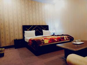 a bedroom with a bed and a table in a room at Hotel Royal Fort in Lahore
